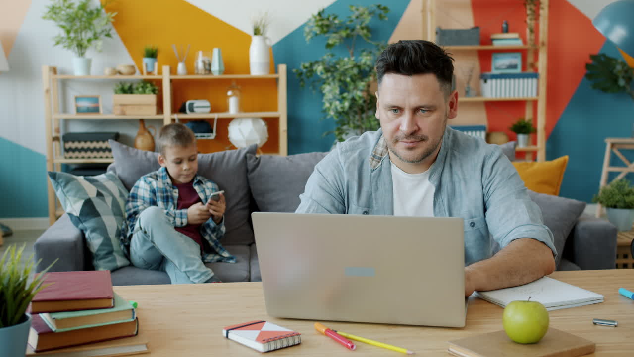 Father Working from Home with Son in the Background