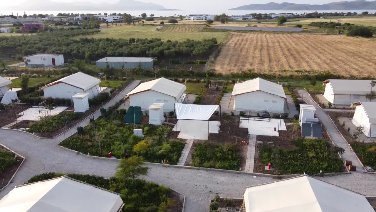 filmación de drones cinematográficos circulando lujosas carpas blancas en un glamping en el campo de una isla griega