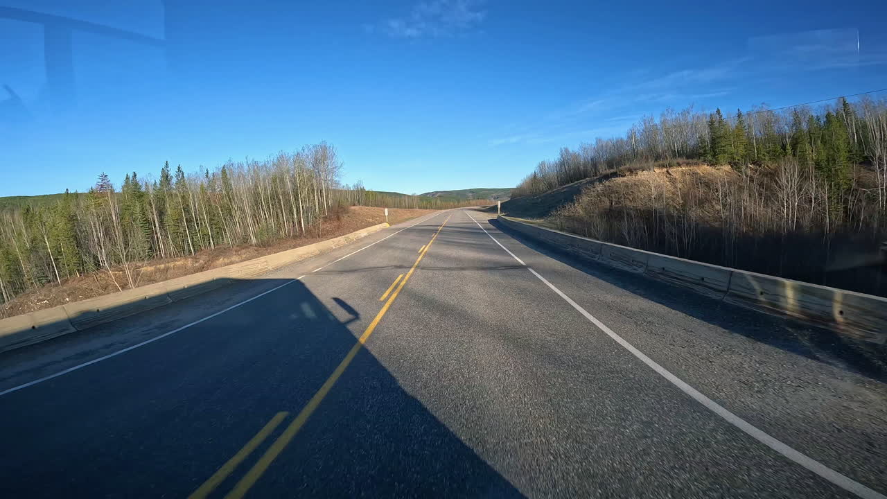 POV - Driving on the Alaska Highway through the Liard River valley in early morning; early summer in Yukon Territory of Canada; concepts of road less traveled and adventure travel