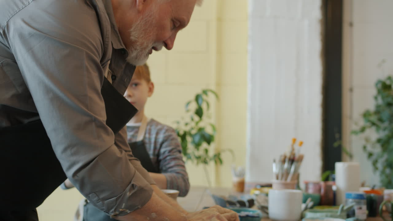 Elderly man teaching pottery to children