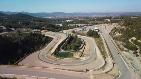 Circuito-De-Velocidad-Castelloli-En-Barcelona-En-Un-Día-Soleado-Con-Pista-Sinuosa-Y-Paisaje-Exuberante,-Vista-Aérea