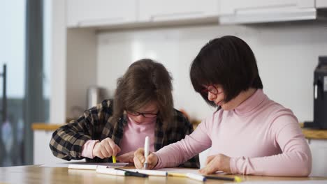 Two-girls-draw-with-colorful-pens-at-home.-Communication-of-kids-with-disabilities