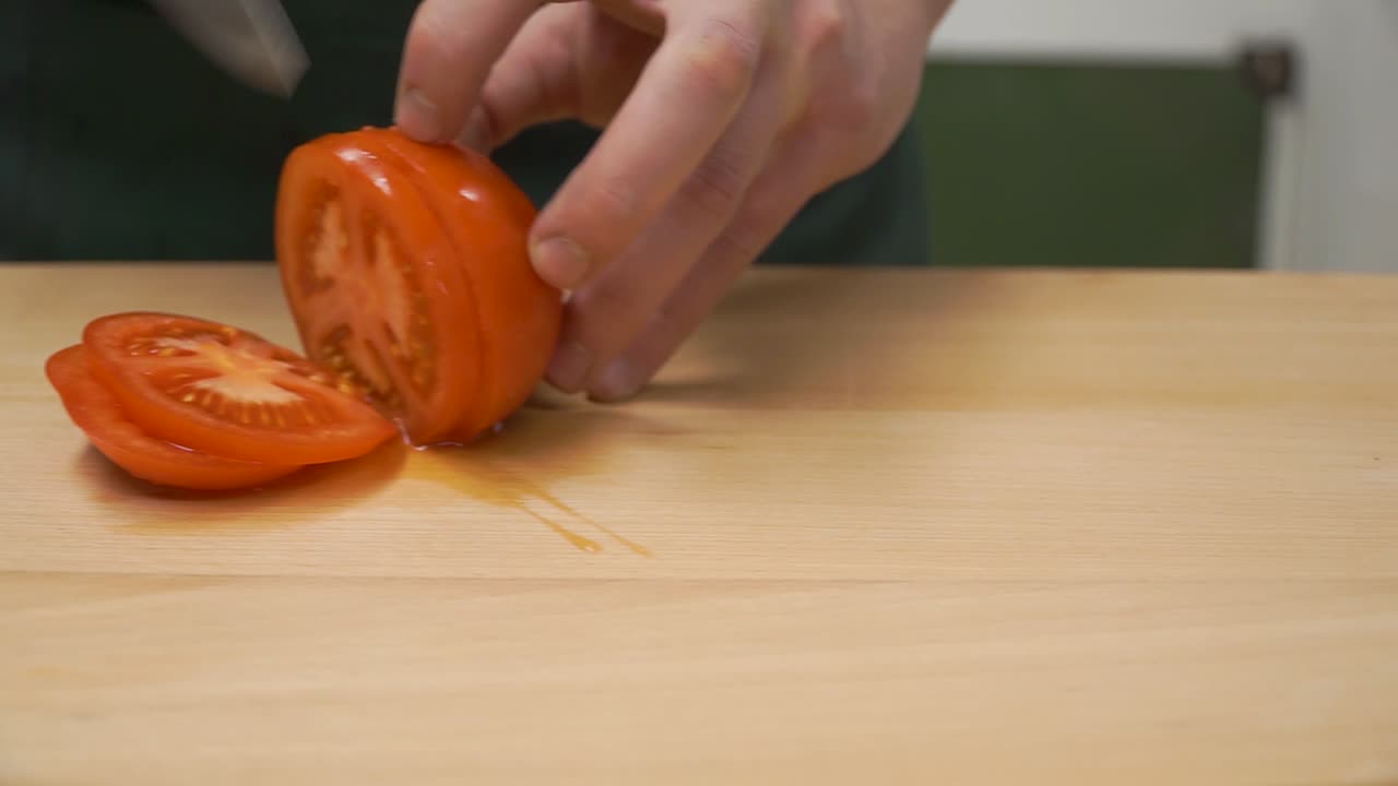 셰프가 토마토를 잘라내고 있습니다.