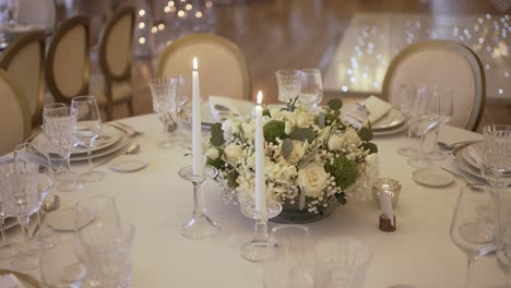elegant table setting with floral centerpiece and lit candles, surrounded by glassware