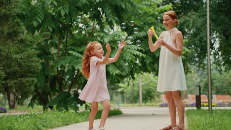 mother and daughter playing with bubbles in the park
