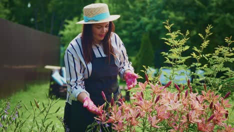 woman gardener in striped shirt and straw hat tending to vibrant flowers in lush garden