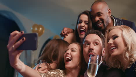 smiling group of friends celebrate evening event with selfie at party