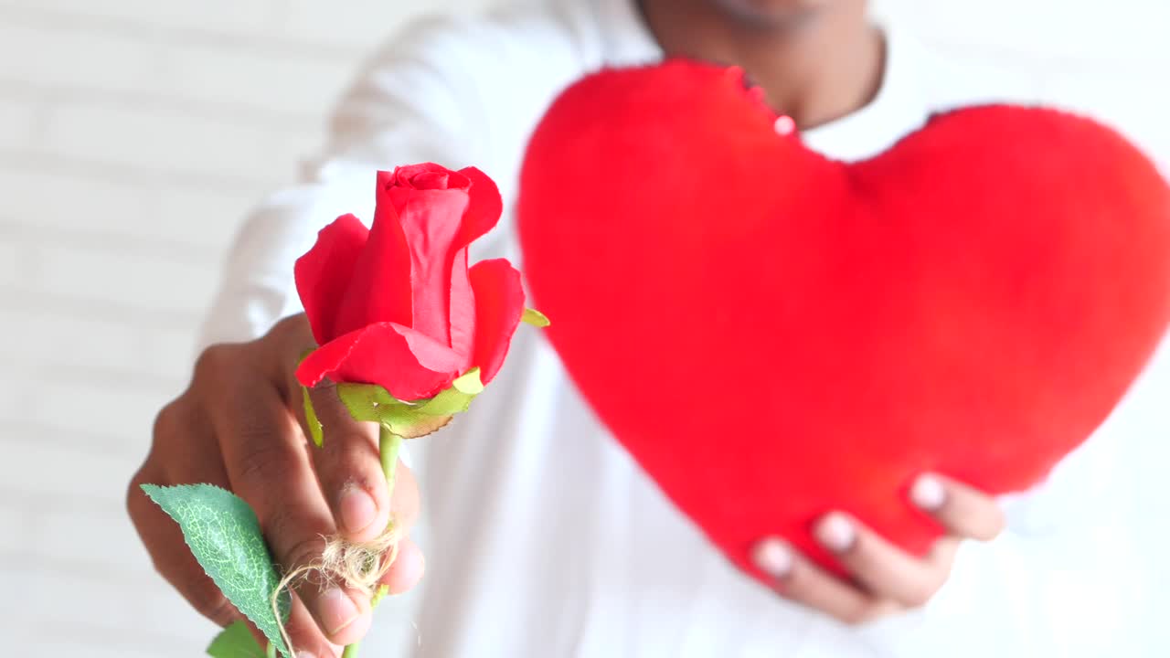 hombre dando una rosa roja y un corazón rojo