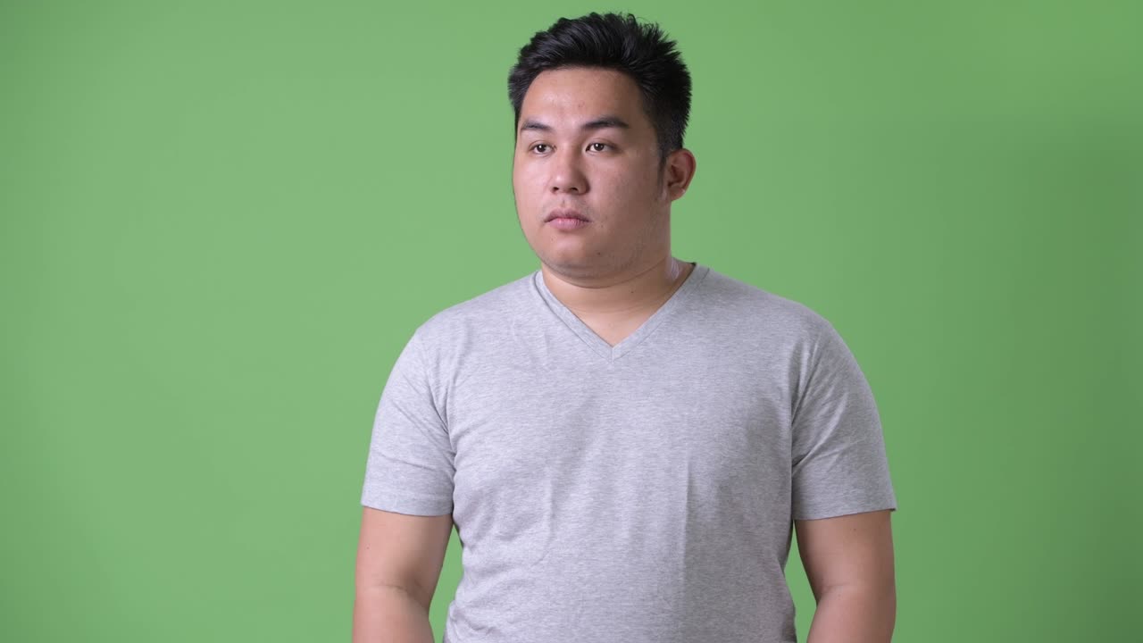 초록색 배경에 젊은 잘생긴 과체중 아시아인