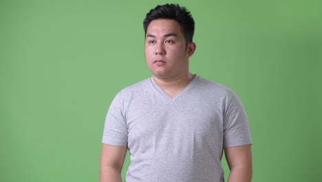 초록색 배경에 젊은 잘생긴 과체중 아시아인