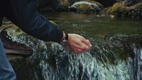 slow motion shot of man washing hands in river water, cumbria