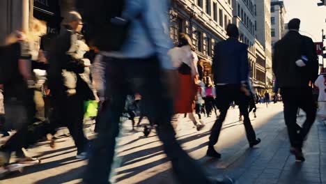 bustling urban sidewalk teeming with businesspeople, shoppers, and tourists moving quickly through metropolitan street during daytime, capturing city's vibrant energy and constant motion