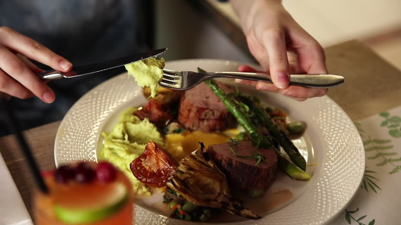Primo piano delle mani che gustano un pasto gourmet con forchetta e coltello