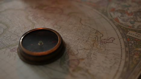 an antique compass on a vintage map by candlelight