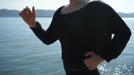 cropped shot of sporty young woman running along embankment