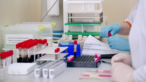 doctor hand taking blood sample tube. hands of lab technician with a tube of blood sample and a rack with other samples