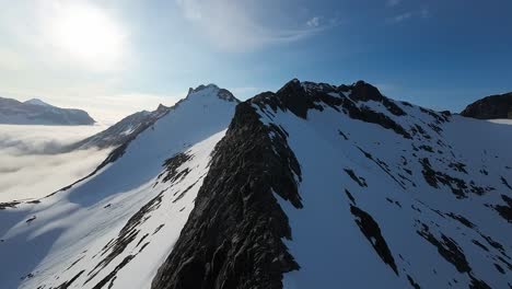 fpv footage from a drone climbing a snowy mountain during midnight sun in northern norway