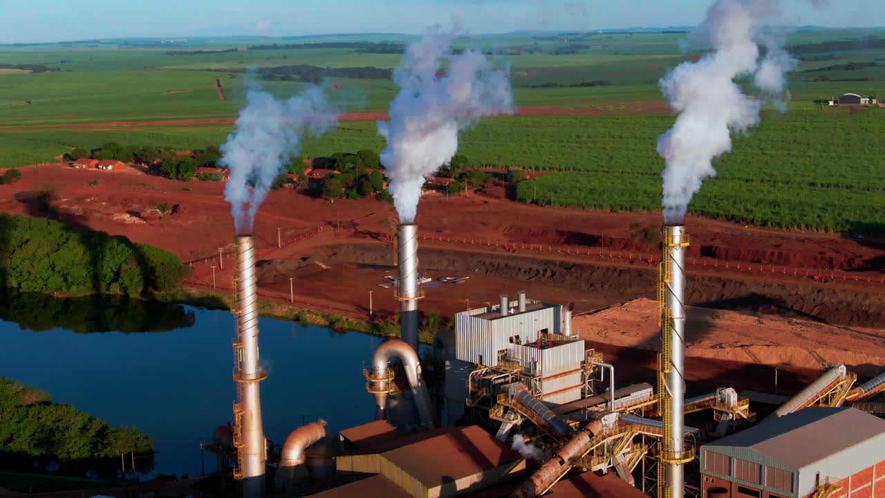 An ethanol production plant with smoke billowing from chimneys, aerial view.