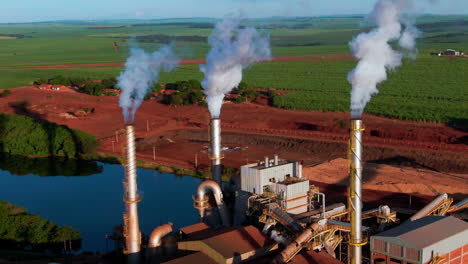 an ethanol production plant with smoke billowing from chimneys, aerial view.