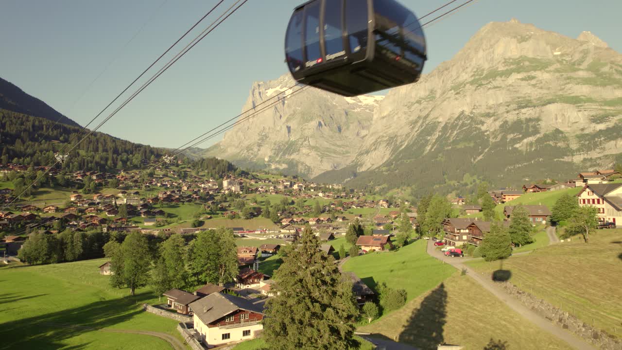 продвигаясь к восходящей кабине тройной канатной дороги эйгер экспресс в гриндельвальде с потрясающим видом на деревню гриндельвальд и гору веттерхорн