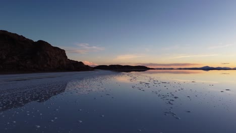 aerial skims water surface of uyuni salt lake in bolivia at sunset