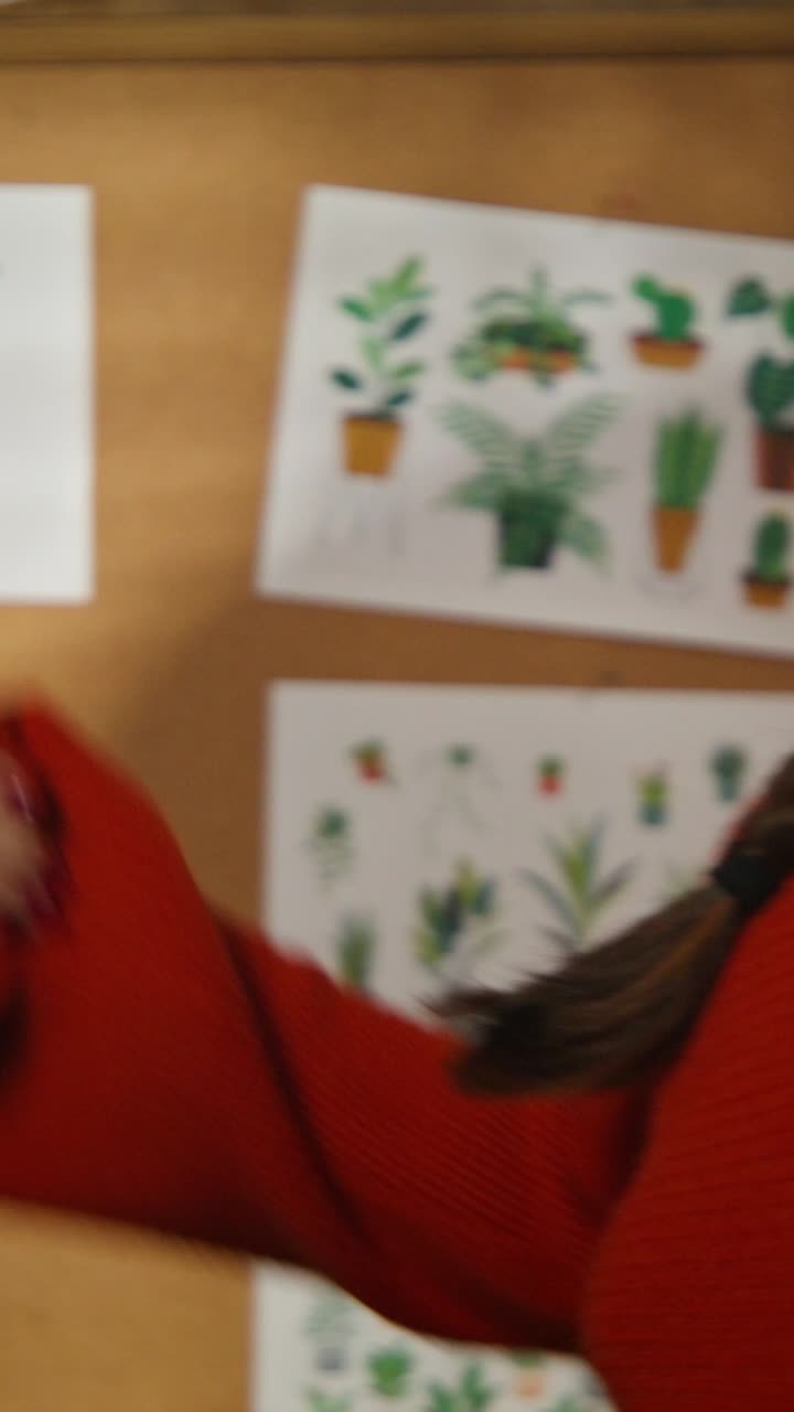 Woman in a red sweater interacting with a plant drawing.