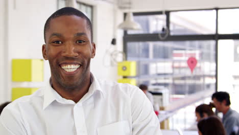 Young-black-man-in-office-walks-into-focus-and-smiles-to-camera