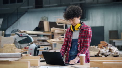 woman woodworker working on laptop in a workshop
