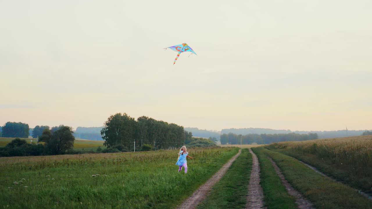 Blij meisje rent met een vlieger in een groen veld in de avond.