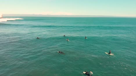 group of surfers waiting and paddling for a wave on a clear morning in the pacific ocean, pichilemu, chile-4k