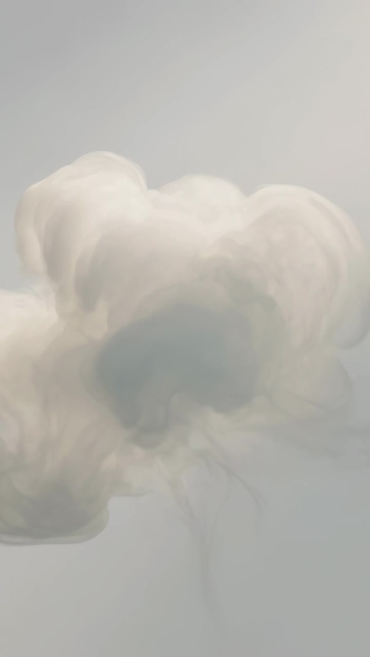 Video verticale: Un pennacchio bianco crescente si diffonde dal centro su uno sfondo grigio, mostrando una luce soffusa.