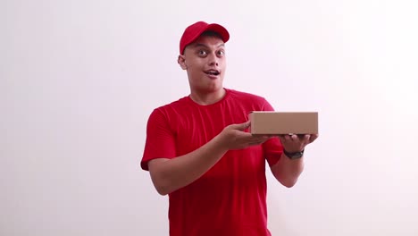 wow asombrado joven mensajero asiático hombre de pie mientras sostiene cartón