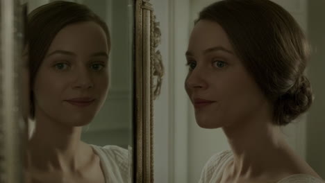 a young woman looking at her reflection in an ornate mirror