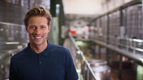 Young-white-man-working-at-a-wine-factory-walking-into-focus