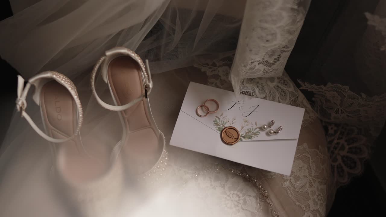 wedding invitation rings earrings and bridal heels arranged on vintage lace fabric