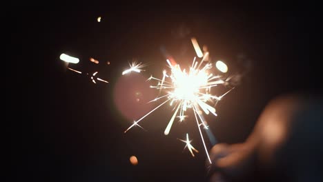 persona sosteniendo petardo phooljhadi en diwali o año nuevo, primer plano, cámara lenta