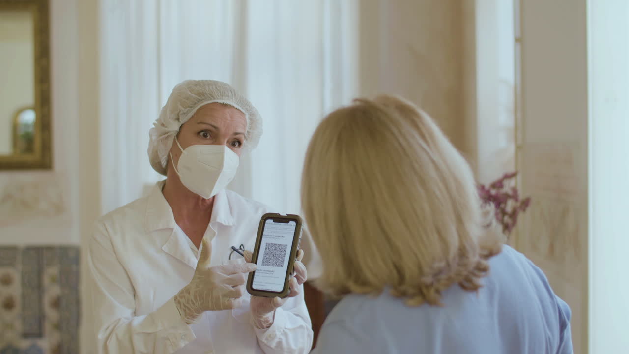 Веселый доктор показывает пожилой женщине QR-код вакцинированного