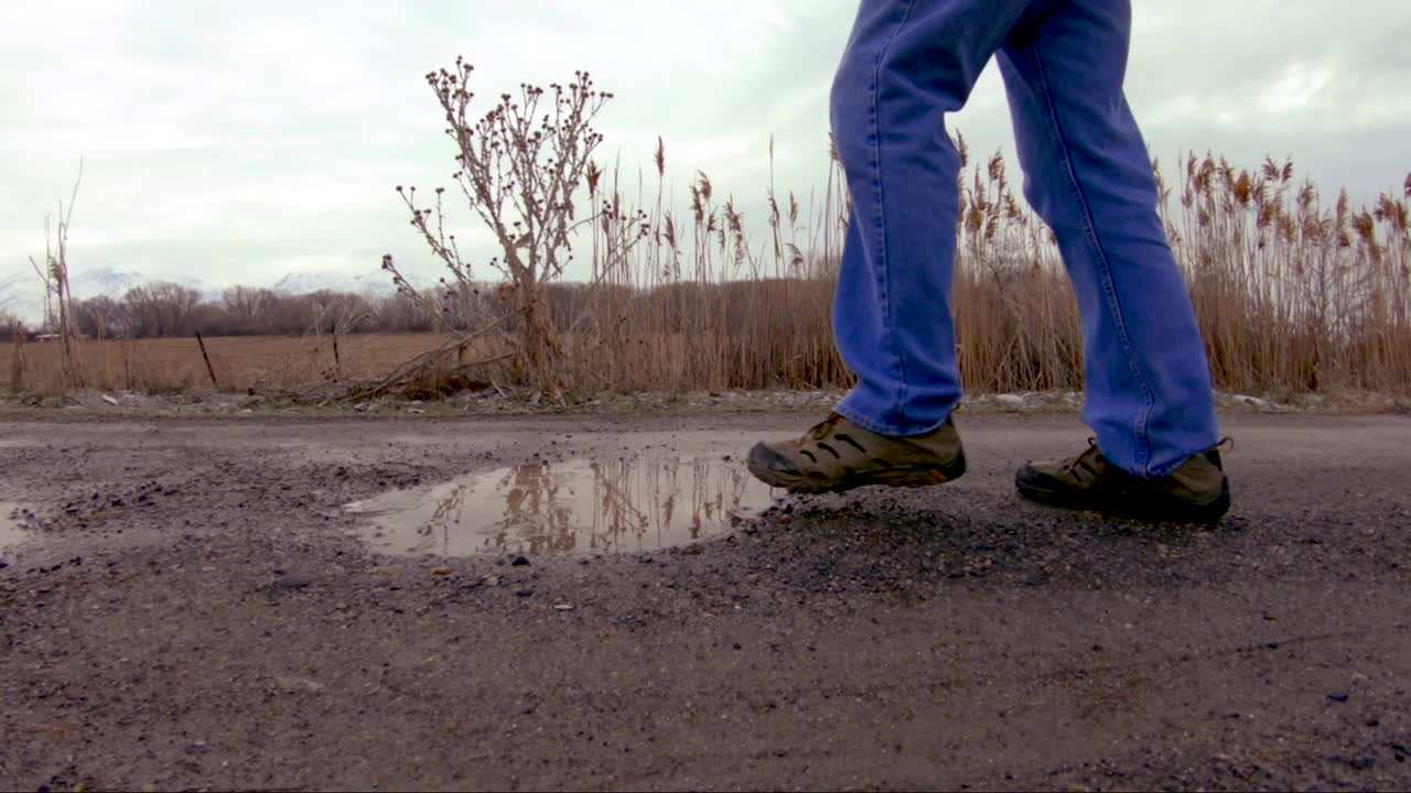 Close-up van een plas waar een man in stapt terwijl hij voorbijloopt - slow motion