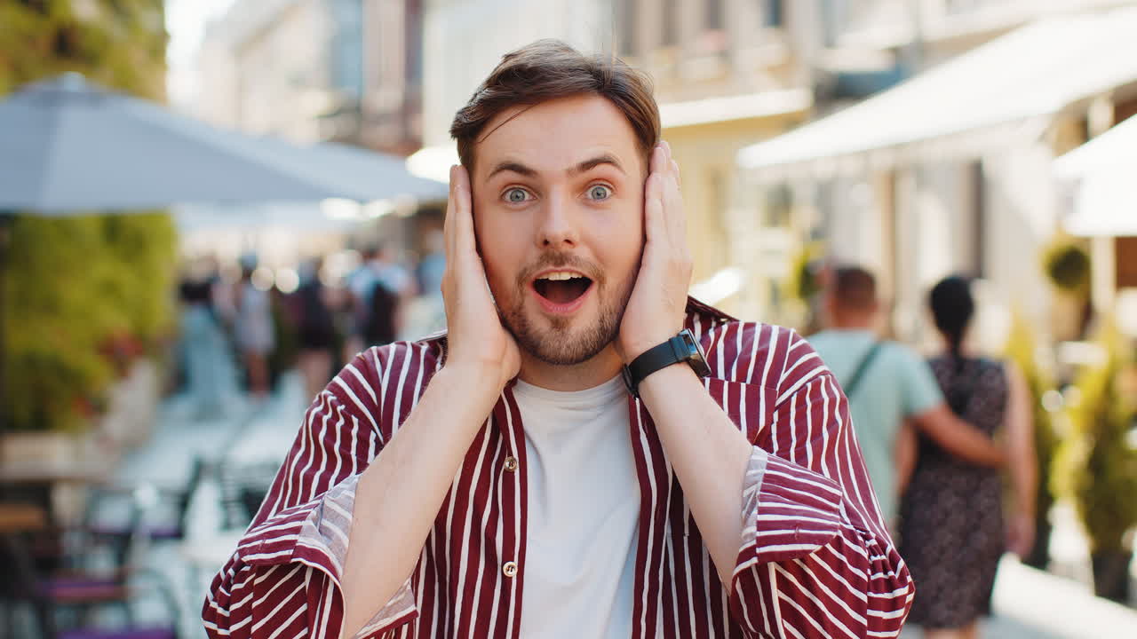 Adult man looking surprised at camera shocked by sudden win good victory news wow in city street