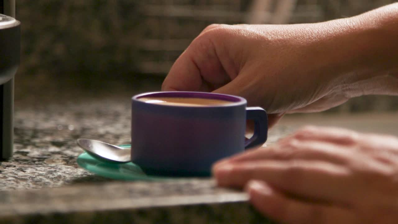 la mano de una mujer recogiendo una taza de café