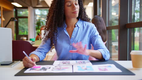 Mujer-De-Negocios-Sentada-En-Un-Escritorio-En-Una-Oficina-Abierta-Aprobando-O-Revisando-Pruebas-O-Diseños-De-Diseño.