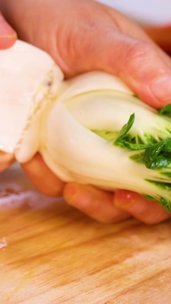 Mani che puliscono e rifilano baby bok choy.
