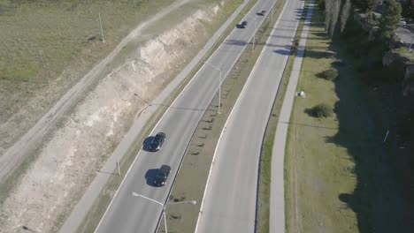 Aerial-Drone-shot-tilting-up-of-highway-with-city-in-the-background,-in-Bahía-Blanca,-Argentina