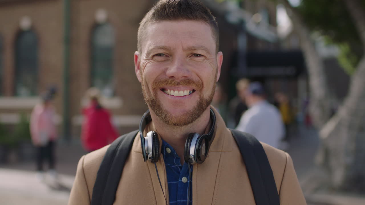 slow motion portrait of charming caucasian man smiling happy in urban background