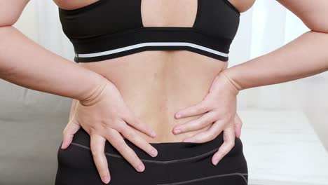 women suffering from back pain and massaging aching muscles and self massage by her hand