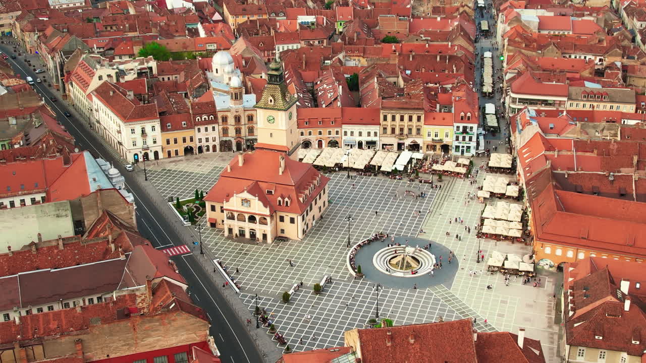 Lotniczy widok z drona na główny plac w Braszowie nocą, Rumunia. Stare centrum miasta z Muzeum Historycznym, Czarnym Kościołem, budynkami, nocnymi światłami, ludźmi