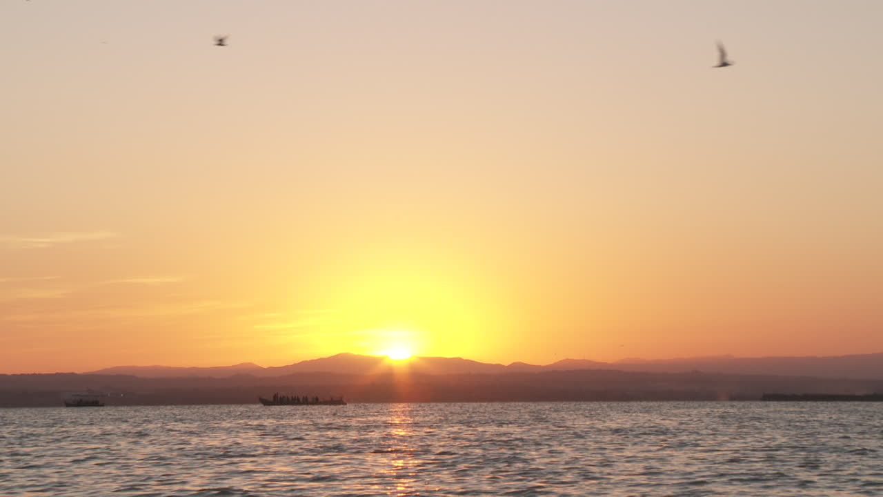 Sunset over the water with boats and people