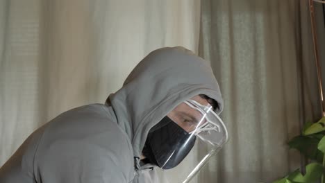 Man-wears-Virus-protection-at-home,-face-shield-and-mask