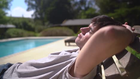 a young boy enjoying relaxation poolside in the warm sunshine - close up