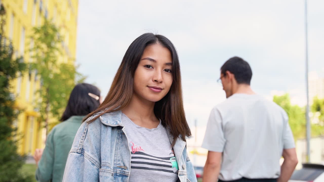 아름다운 일본 소녀가 두 친구를 껴안고 거리에서 그들과 함께 걷고, 얼굴을 돌리고 카메라를 보며 미소를 짓는 모습